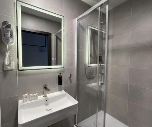 a bathroom with a sink and a shower with a mirror at WE Hotel EXPO Prague in Prague