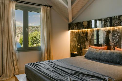 a bedroom with a bed and a large window at Braunis Horio Villas in Asos