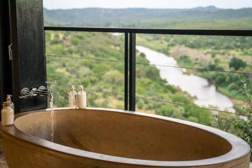 a bath tub in a window with a view of a river at The Outpost in Makuleke Contract Park
