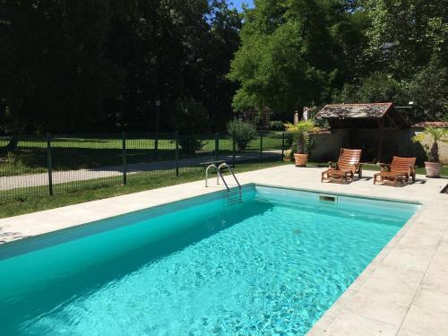 a blue swimming pool with two chairs and a gazebo at Château de Montabert in Montaulin