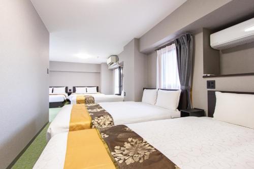 a hotel room with three beds and a window at The LANG HOTEL in Fukuoka