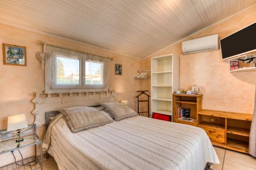 a bedroom with a bed and a window and a tv at Chez Gaston - Chambre in Saint-Drézéry