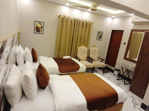 a hotel room with two beds and chairs in it at Hotel BlueSky Clifton 2 in Dargai