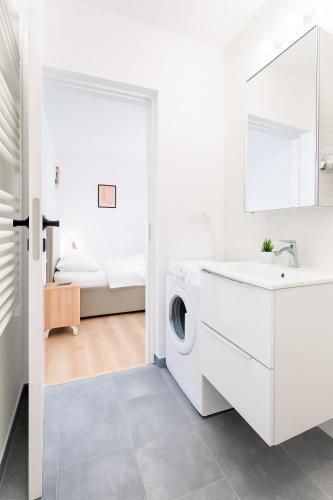 a white bathroom with a sink and a washing machine at Therme Voyage Studio 6 in Otopeni