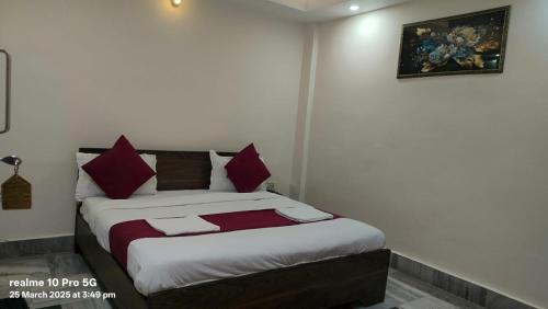 a bedroom with a bed with red and white pillows at New Shanti Hotel in Prayagraj