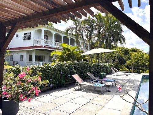 a house with a patio with chairs and an umbrella at VILLA COLIBRI in Mon Repos