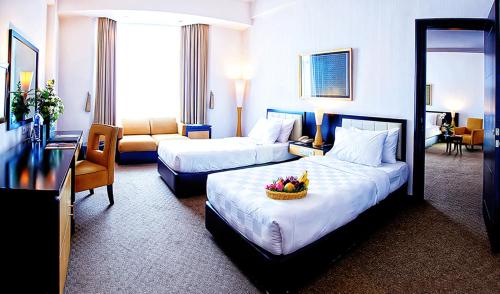 a hotel room with two beds and a couch at Grand Jatra Hotel Pekanbaru in Pekanbaru