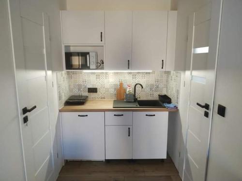 a white kitchen with white cabinets and a sink at Agroturystyka Polana Giebułtów obok Świeradowa i zamku Czocha, domki przyjazne rodzinom z dziećmi in Mirsk