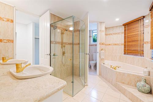 un bagno con doccia, lavandino e vasca di Villa San Michele a Coolum Beach