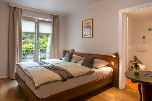 a bedroom with a bed with a table and a window at Hotel Heintz in Vianden