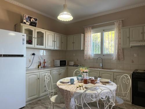 una cucina con mobili bianchi e un tavolo con sedie di Maria's Cottage a Città di Lefkada