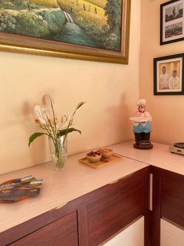 a desk with a vase of flowers and a painting at Ken Hotel by Tripletree in Sampal 2