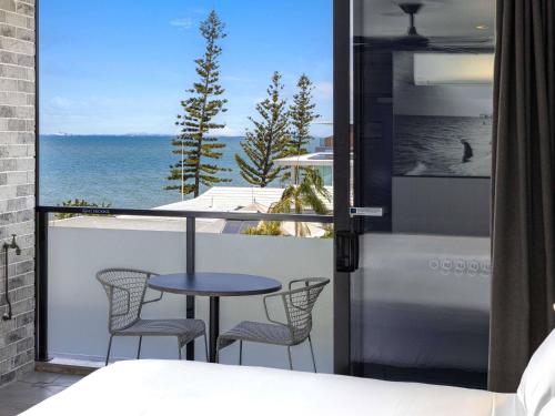 a room with a balcony with a table and chairs at The Sebel Brisbane Margate Beach in Redcliffe