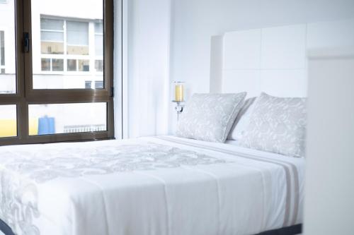 a white bed in a room with a window at GemAn1 in Monforte de Lemos