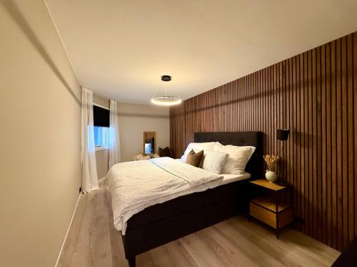 a bedroom with a large bed with a wooden wall at Fjord and Mountain View in Tromsø