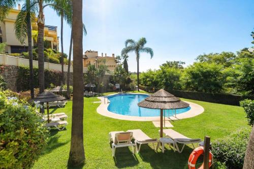 ベナアビスにあるLos Pinos 104 - Precioso 3 - BR cerca de Marbellaの庭園内のプール(椅子、パラソル付)