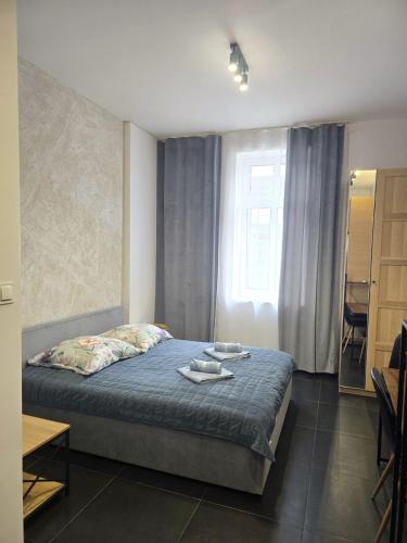 a bedroom with a bed with a blue blanket and a window at MH Apartment in Rzeszów