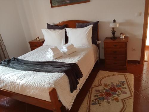 a bedroom with a bed with white sheets and pillows at Casa do Campo in Seia