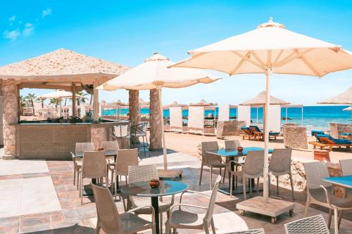 a restaurant with tables and umbrellas on the beach at Pickalbatros Citadel Resort Sahl Hasheesh in Hurghada