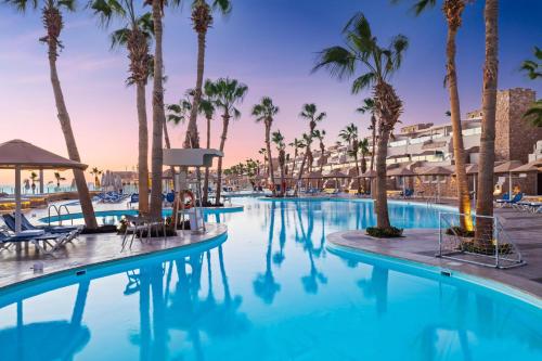 a swimming pool with palm trees and a resort at Pickalbatros Citadel Resort Sahl Hasheesh in Hurghada