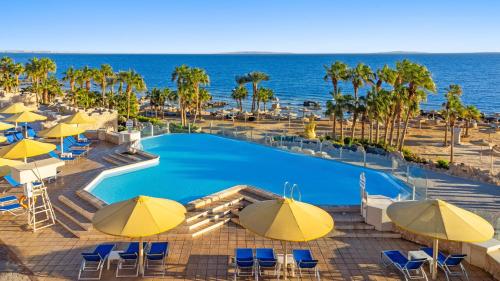 a pool with umbrellas and chairs and the ocean at Pickalbatros Citadel Resort Sahl Hasheesh in Hurghada