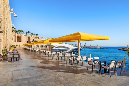 a row of tables and chairs with umbrellas and the water at Pickalbatros Citadel Resort Sahl Hasheesh in Hurghada