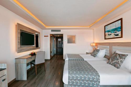 a hotel room with two beds and a desk at Pickalbatros Citadel Resort Sahl Hasheesh in Hurghada