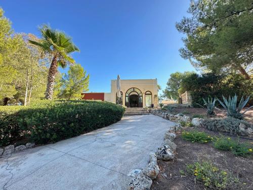 Un camino de entrada que conduce a un edificio con una palmera. en Agriturismo Il Trappeto, en Gallipoli