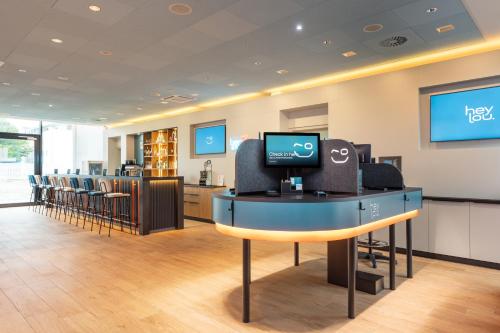 a waiting room with a computer on a desk with chairs at Hey Lou Hotel Friedrichshafen in Friedrichshafen