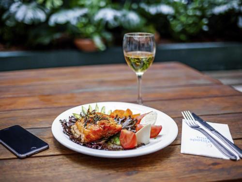 a plate of food and a glass of wine on a table at ibis Styles Rio de Janeiro Botafogo in Rio de Janeiro