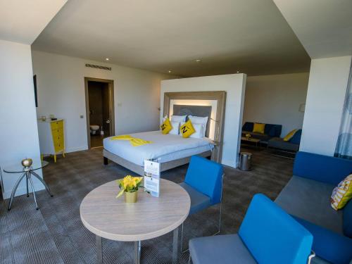 a room with a bed and a table and chairs at Novotel Mohammedia in Mohammedia