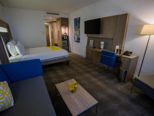 a hotel room with a bed and a couch and a table at Novotel Mohammedia in Mohammedia