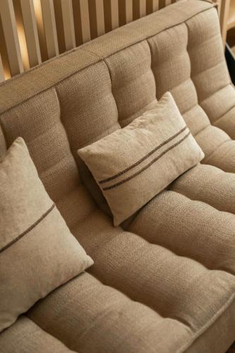 a couch with two pillows on top of it at La Barzalière in Chimay