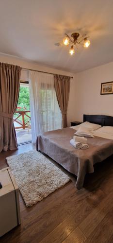 Un dormitorio con una cama y una ventana grande. en Pensiunea Gold, en Durau