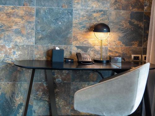 a table with a lamp and a phone and a chair at SO/ Auckland in Auckland