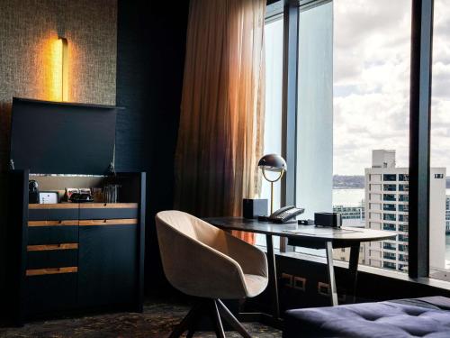 a desk and chair in a room with a window at SO/ Auckland in Auckland