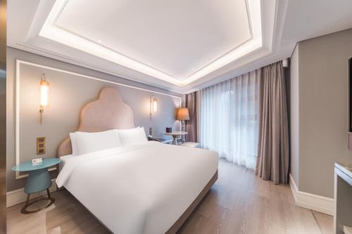 a bedroom with a large white bed and a window at Mercure Shenzhen Sports Center Hotel in Shenzhen