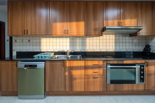 a kitchen with wooden cabinets and a sink and a stove at Veer Apartments - 87th Floor Penthouse Full Sea View 5 BHK in Dubai