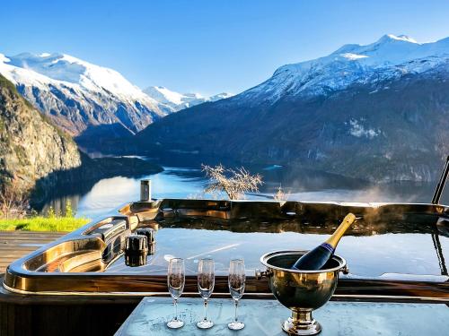 a table with wine glasses and a bath tub with mountains at Lingåsen Panorama! in Valldal