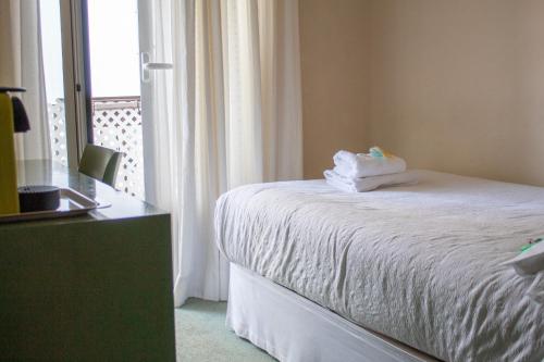 a bedroom with a bed with white sheets and a window at Hostal Navarra in Pamplona