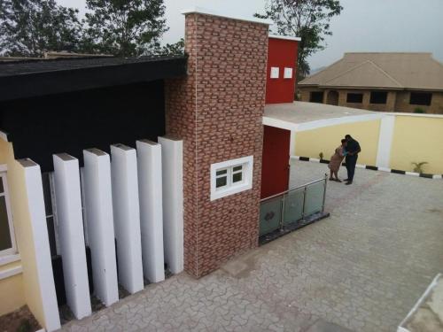 a brick building with white doors and people walking outside at Rikkies Place Hotel in Lagos