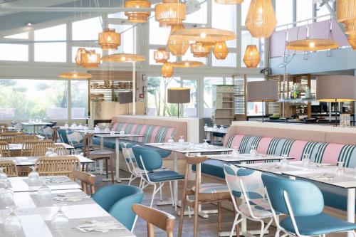 a restaurant with tables and chairs and chandeliers at Belambra Clubs Capbreton - Les Vignes in Capbreton