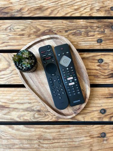 two remote controls sitting on a wooden plate at Cocon au cœur du centre ville de Bazas in Bazas