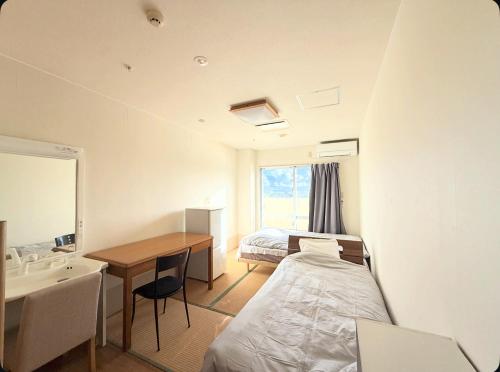 a bedroom with a bed and a desk and a sink at ハイ沖縄金武店トイレお風呂共用 プレオープン中駐車場有 ペット同伴可能長期滞在可能2025年10月より車貸し出しサービス有希望であればお申し付けください in Kin