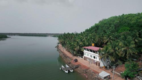 a house on the side of a river with palm trees at Nadhi Mane River-front Beach Stay in Tadri