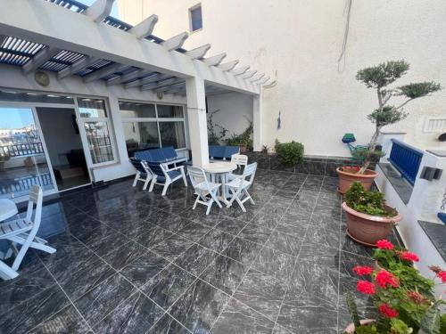 a patio with white chairs and tables and a white building at Monastir duplex with terrace in Monastir