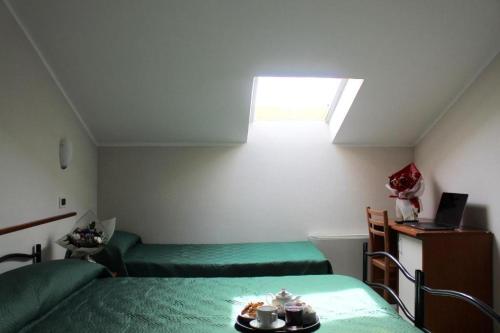 Habitación pequeña con cama y escritorio con ordenador portátil. en Bleu Hotel, en Cesenatico