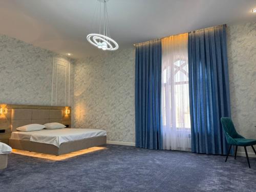 a bedroom with a bed and a window with blue curtains at Turkistan in Türkistan