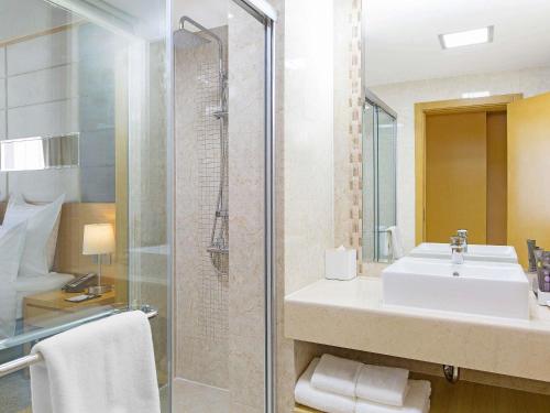 a bathroom with a sink and a shower at Novotel Ulaanbaatar in Ulaanbaatar