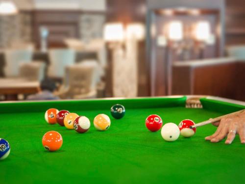 a man is playing billiard on a pool table at Novotel Ulaanbaatar in Ulaanbaatar
